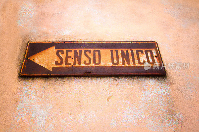 粉红色墙上的意大利单向标志(“SENSO UNICO”)生锈了